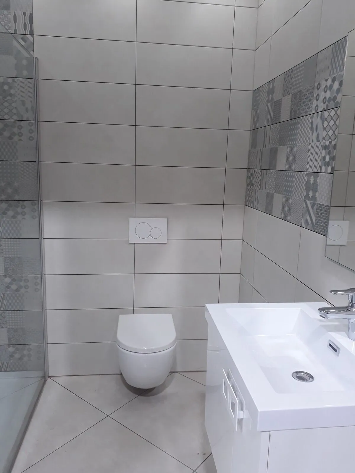 Salle de bain rénovée avec WC suspendu et carreaux décoratifs – IDGS Constructions, région de Schilde