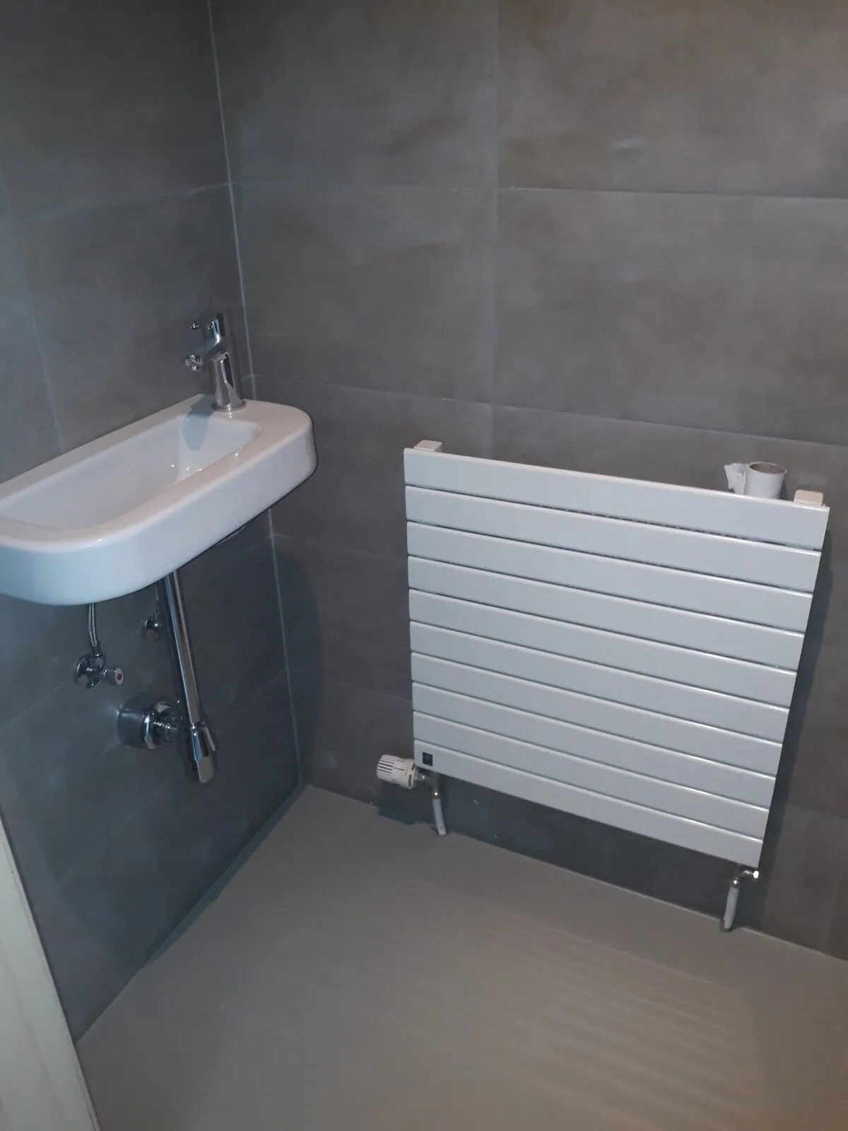 Toilettes avec lave-mains, radiateur design et carrelage anthracite – IDGS Constructions, région de Zaventem