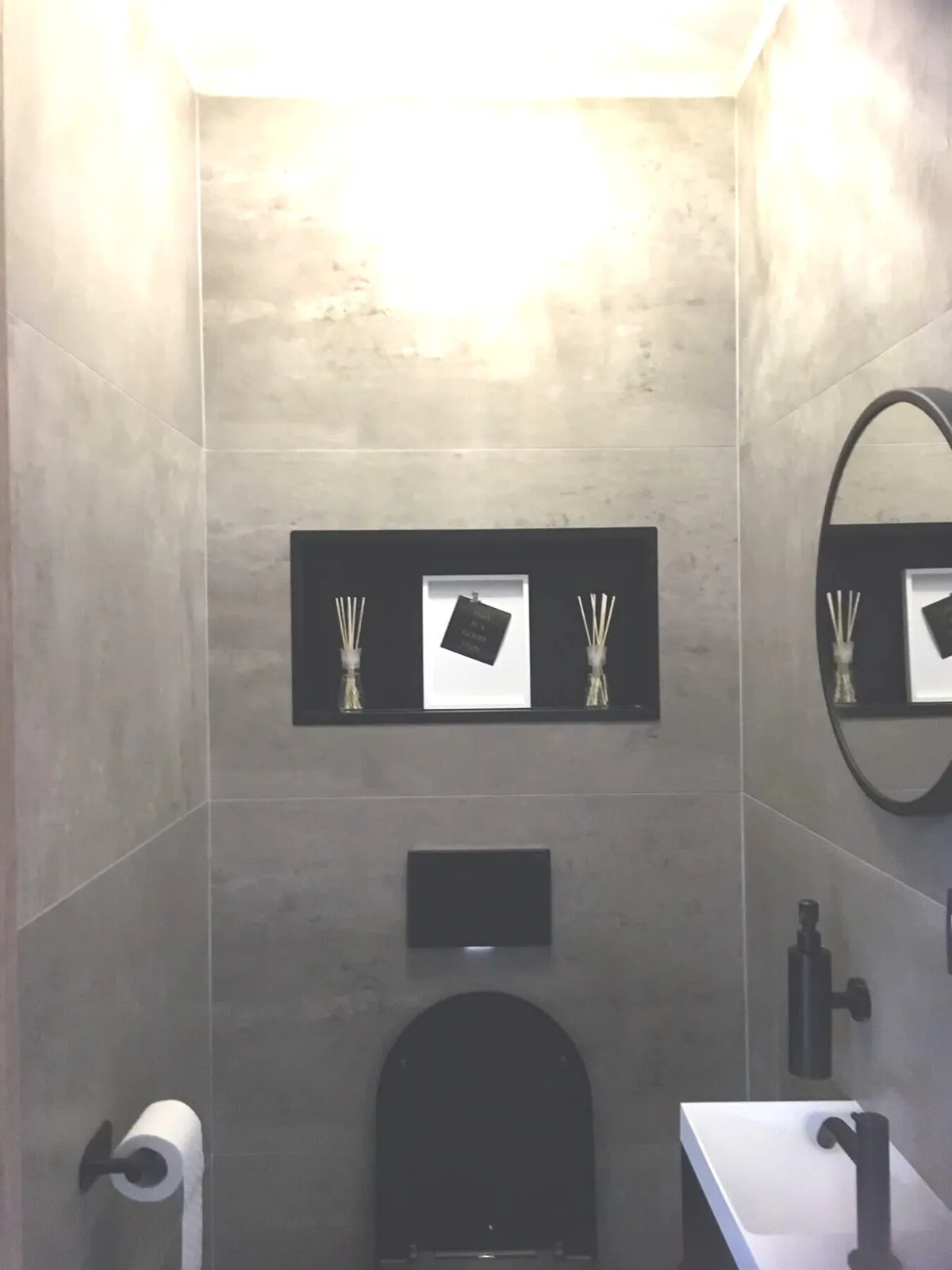 Toilettes rénovées avec carrelage effet béton, WC suspendu et niche à Anvers