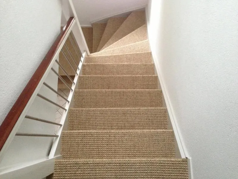Escalier rénové avec tapis en sisal et rampe blanche à Anvers