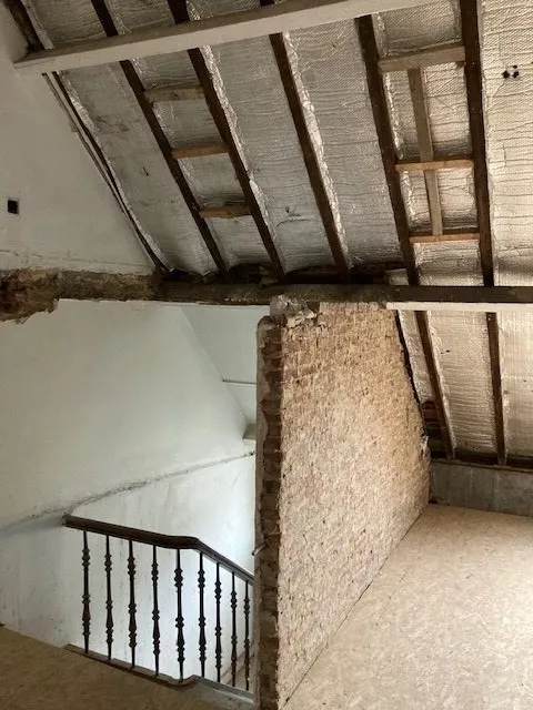 Cage d'escalier et grenier avec charpente apparente avant la rénovation à Anvers