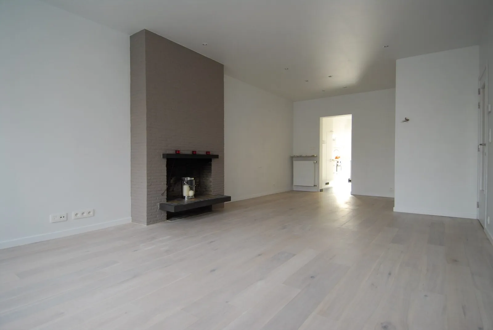 Séjour lumineux avec parquet et cheminée après rénovation – IDGS Constructions, région de Malines