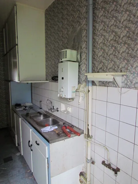 Ancienne cuisine avec chauffe-eau avant rénovation – IDGS Constructions, région de Bruxelles
