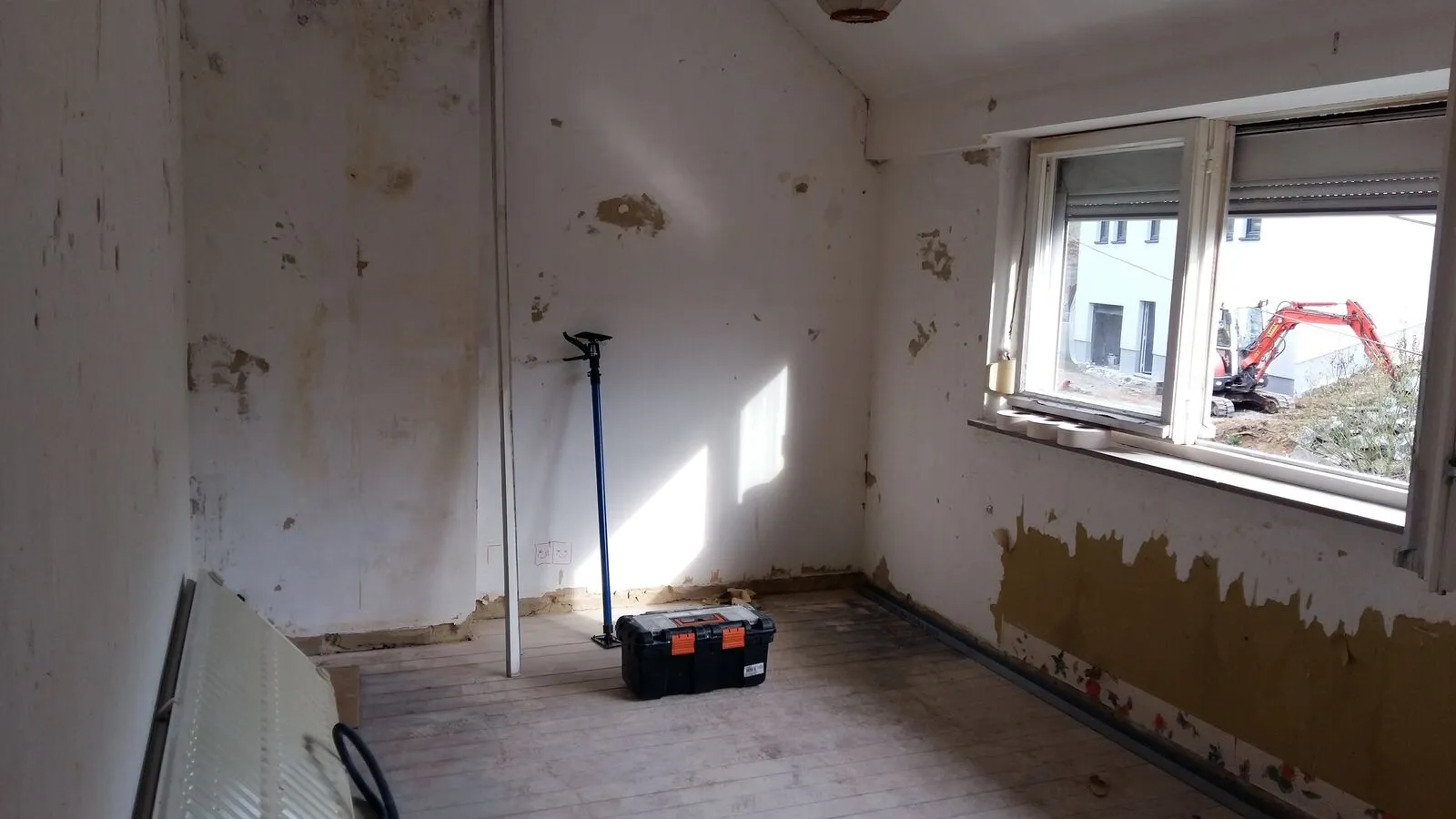 Cuisine vidée aux murs abîmés avant la rénovation à Rixensart